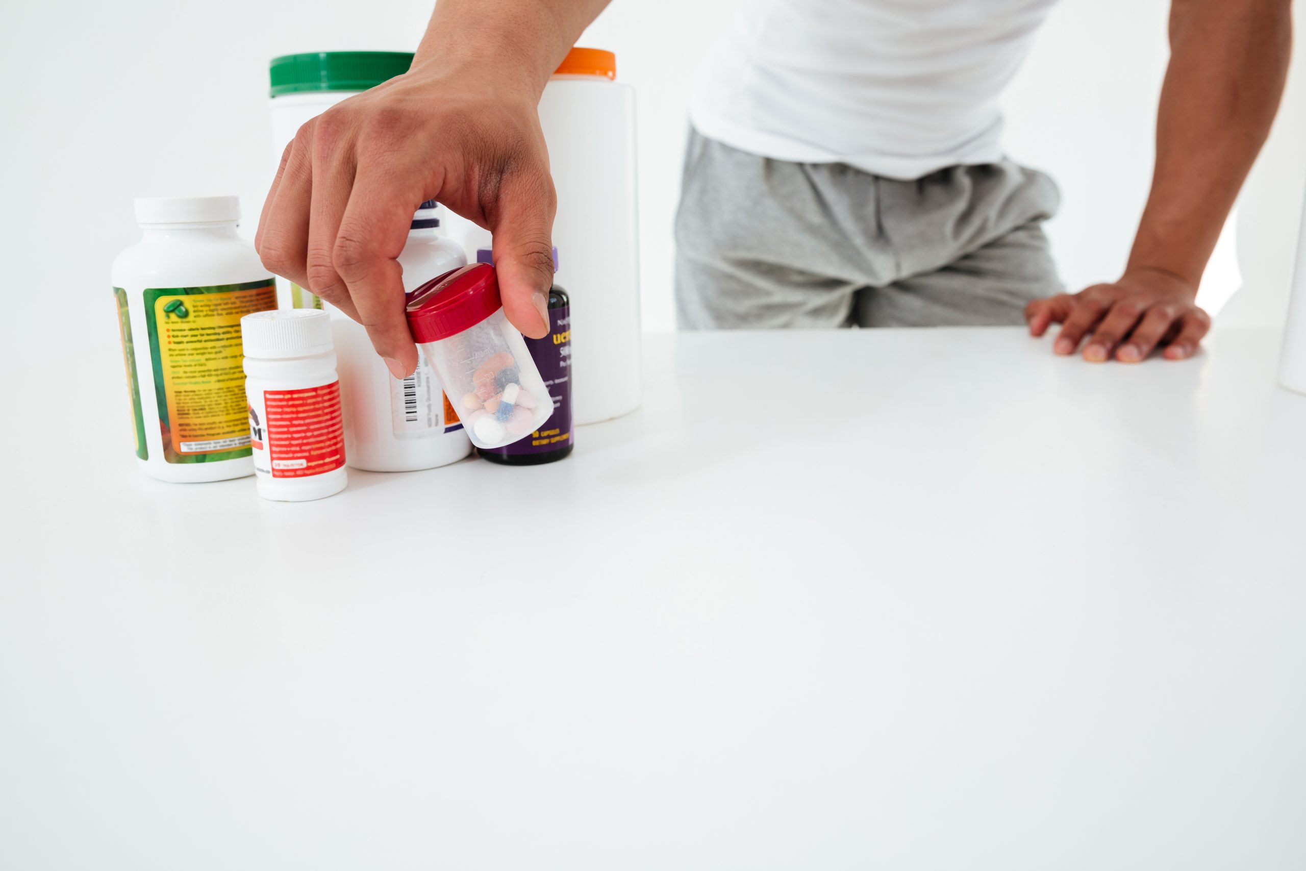 Cropped image of handsome young sportsman holding vitamins