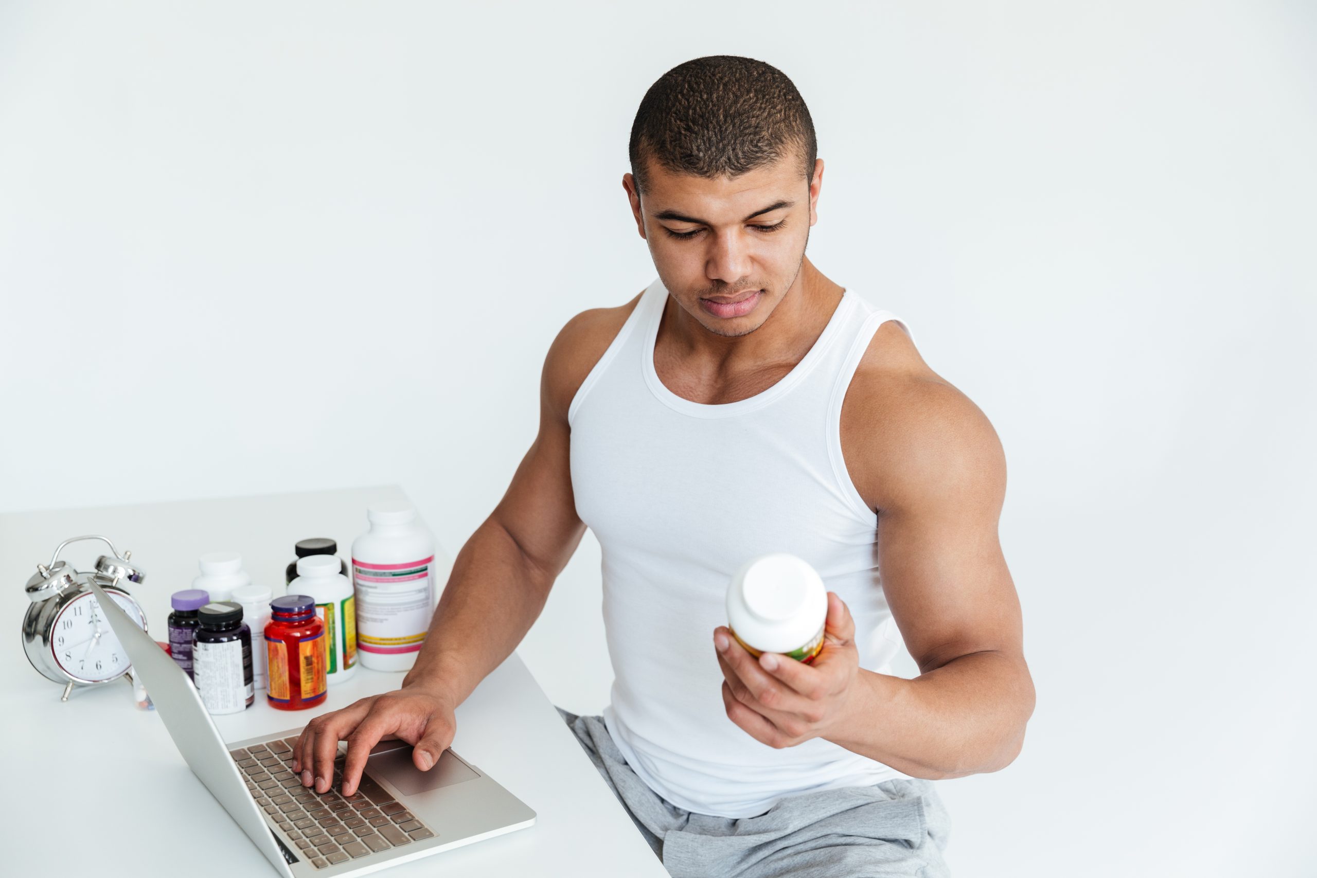 Handsome young sportsman holding sport nutrition and using laptop computer handsome-young-sportsman-holding-sport-nutrition-using-laptop-computer Health supplements south africa